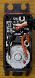 The insides of a typical servo motor. On the bottom, a 2-wire DC motor. On top, a circuit board that runs the control system and interprets servo commands.